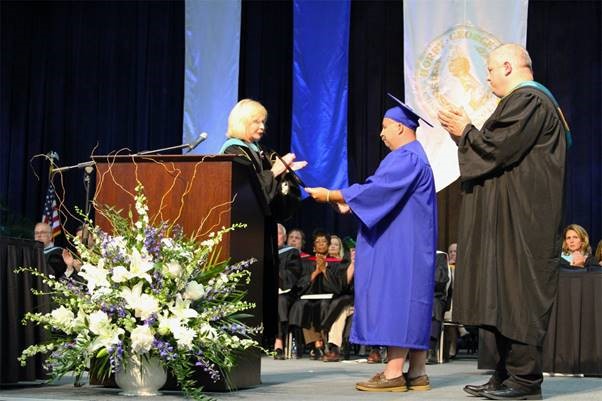 EMT student Bill Rosas and Professor Scott Cyganiewicz accept a posthumous degree for Daniel Roy, who passed away in March.