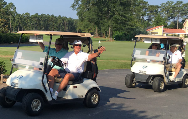 Golf players ride along in golf carts