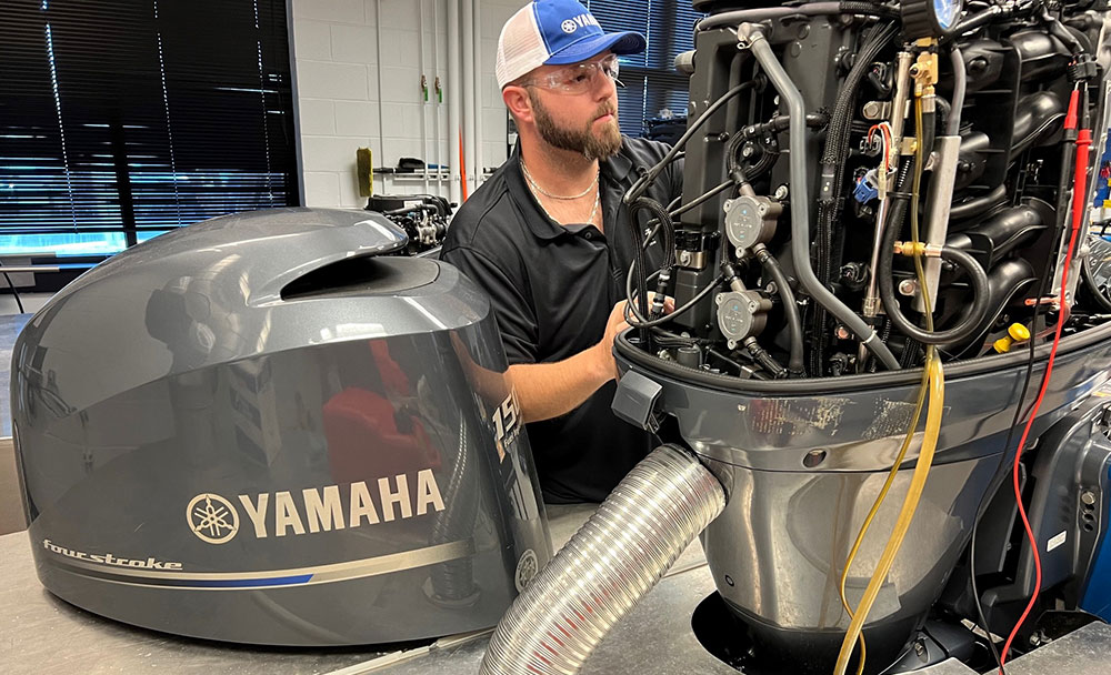 A man works on a Yamaha engine