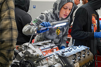 a student shining a light on an engine