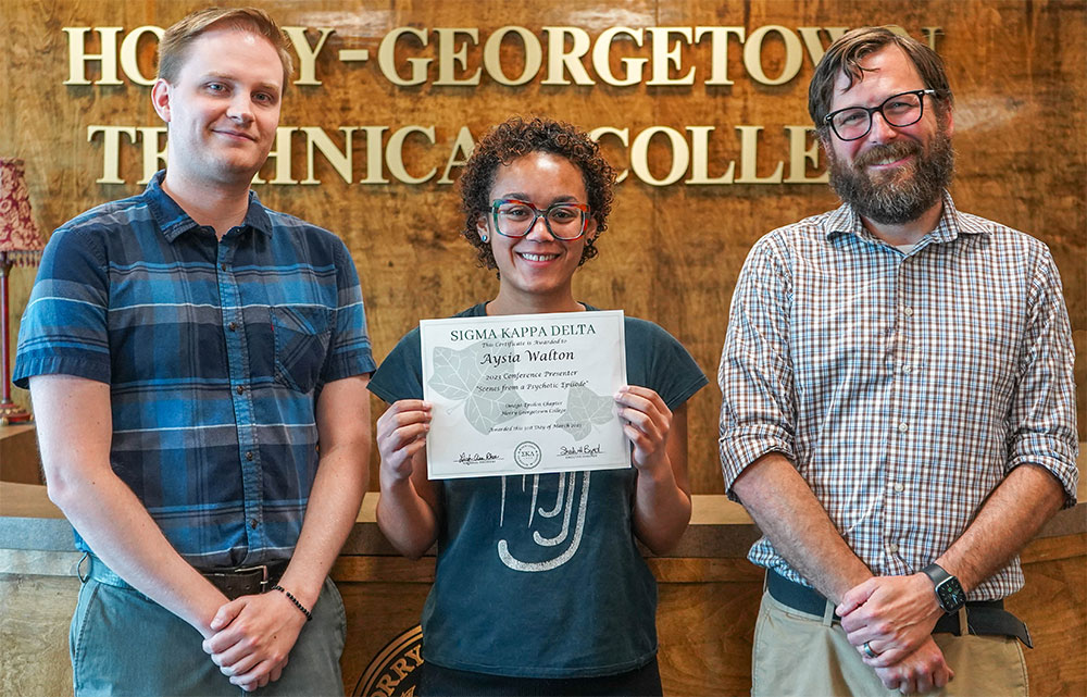 a student and two professors standing with an award